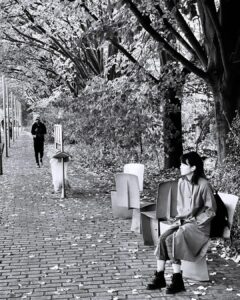 Femme assise et passant parc de la Villette