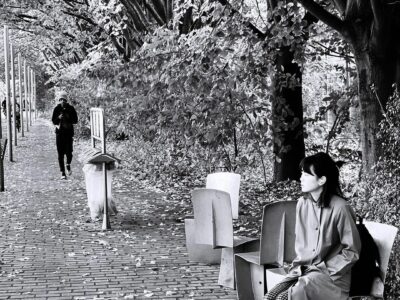 Femme assise et passant parc de la Villette